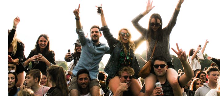 happy young people in a crowd with some sitting on shouldres